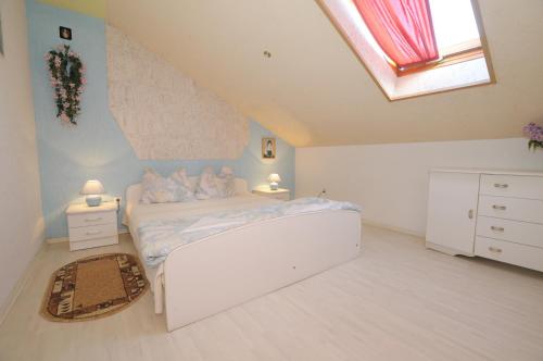 a bedroom with a white bed and a skylight at Cztery Pory Roku in Grzybowo