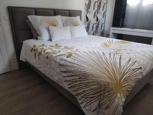 um quarto com uma cama grande com lençóis brancos e dourados em Chambres d'hôtes Elcy 