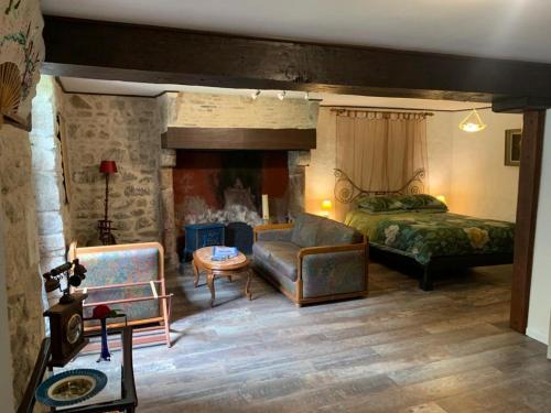 1 dormitorio con cama, sofá y chimenea en Moulin de chez Joyeux, en Thiat