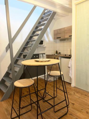 a table and two stools in a kitchen with a staircase at Logement au coeur de dole in Dole