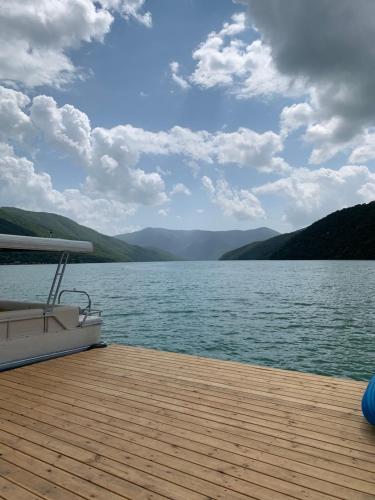 a boat on a lake with mountains in the background at Panorama ananuri guest house in Ananuri