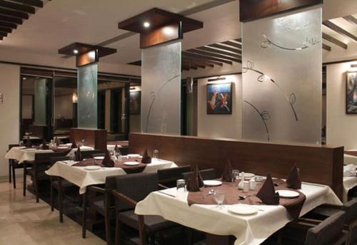 um restaurante com mesas e cadeiras e um espelho em Hotel Kanan em Ahmedabad
