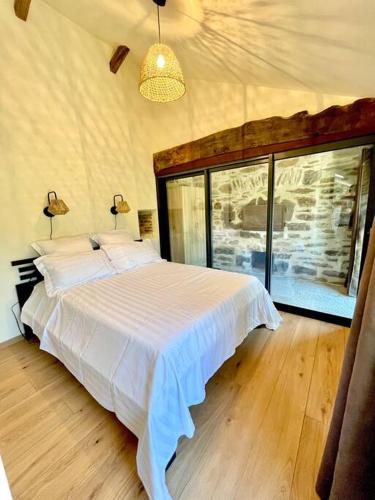 une chambre avec un lit blanc et une grande fenêtre dans l'établissement Dépendance corps de ferme, à Naucelles