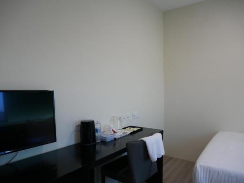 a room with a bed and a desk with a television at Pantai Regal City Hotel in Kuantan