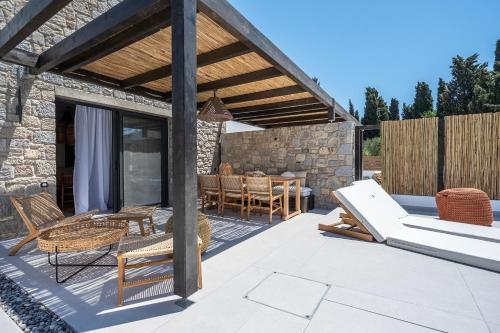 a patio with a deck with chairs and a table at RASTONI VILLAS BY AEGEAN HOUSES in Psalidi
