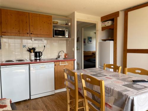 a kitchen with a table and a white refrigerator at Appartement 2 chambres vue exceptionnelle in Chamrousse