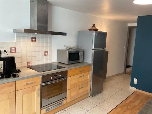 a kitchen with a stainless steel refrigerator and a microwave at Appartement indépendant 