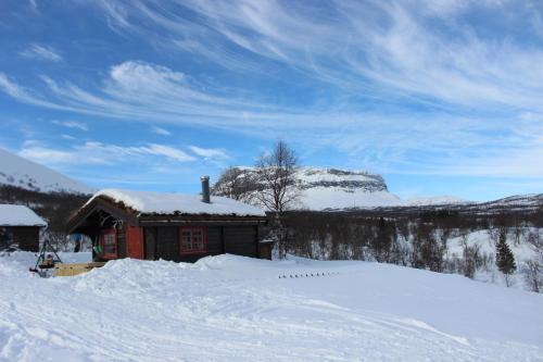une cabane en rondins dans la neige avec une montagne en arrière-plan dans l'établissement Mountain cabin Skoldungbu, à Vang I Valdres