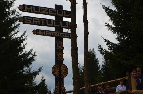 a pole with street signs in front of people at Pensiunea Popasul Iancului in Mărişel