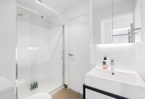a white bathroom with a shower and a sink at Apartment with Brilliant views in Auckland CBD in Auckland