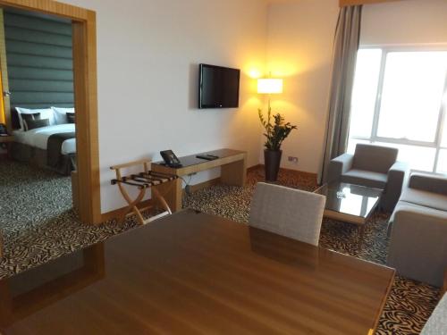 a living room with a table and a room with a bed at Copthorne Hotel Sharjah in Sharjah