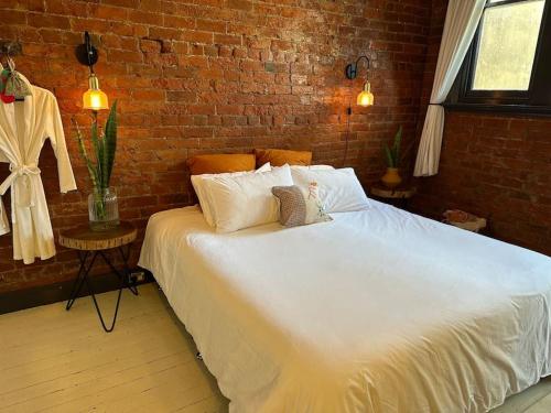a bedroom with a white bed with a brick wall at The Old Chocolate Shop in Canowindra