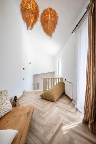 a living room with a wooden floor and two hanging lights at RASTONI VILLAS BY AEGEAN HOUSES in Psalidi