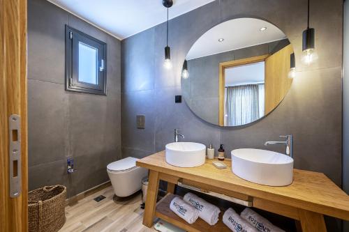 a bathroom with two sinks and a mirror at RASTONI VILLAS BY AEGEAN HOUSES in Psalidi