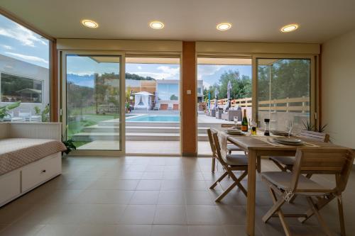 a dining room with a table and chairs and sliding glass doors at Modular Bungalows With Heated Pool Artemis Greece in Artemida