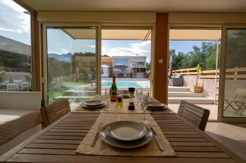 uma mesa de jantar com pratos e copos de vinho no pátio em Modular Bungalows With Heated Pool Artemis Greece em Artemida