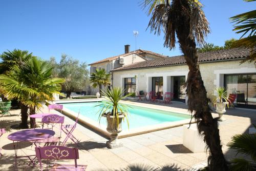 une piscine avec des chaises violettes et une maison dans l'établissement Maison avec piscine et jacuzzi, à Sigogne