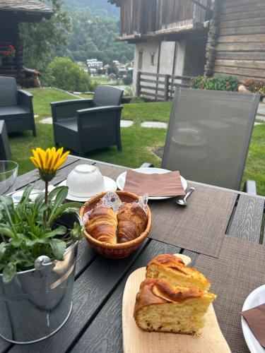 a table with bread and a basket of pastries on it at L'Abreny in Brusson