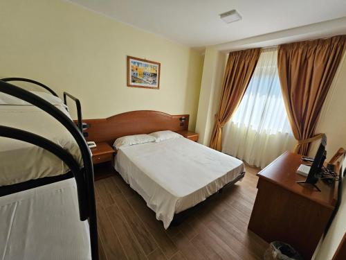 a hotel room with a bed and a desk and window at Hotel Dimora Adriana in Tivoli