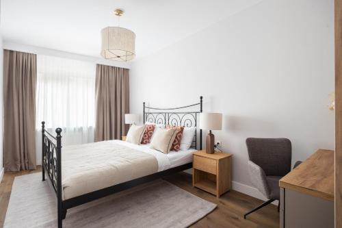 ein Schlafzimmer mit einem schwarzen Bett und einem Stuhl in der Unterkunft Metro Kabaty Elegant Apartment by BookingHost in Warschau