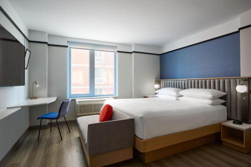 een slaapkamer met een bed, een bureau en een stoel bij Delta Hotels by Marriott New York Times Square in New York