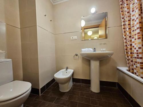 y baño con lavabo, aseo y espejo. en 1A106 Amplio y cómodo apartamento, en Gijón