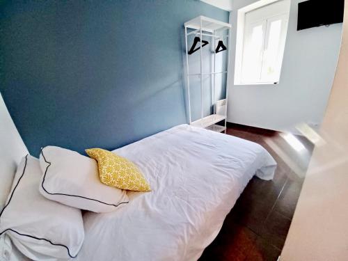 - une chambre avec un lit blanc et un oreiller jaune dans l'établissement Le Peyragudes - Rue de la Grotte - 36m, à Lourdes