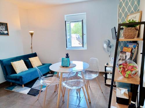 a living room with a table and a blue couch at Le Peyragudes - Rue de la Grotte - 36m in Lourdes