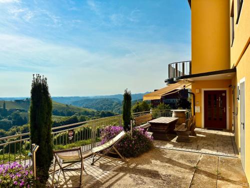 a house with a patio with a bench and flowers at Apartment Weingartenblick - Glanzerhof in Gamlitz