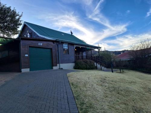 un garage con una porta verde per garage su una casa di Mystic Mountain Cottage a Clarens