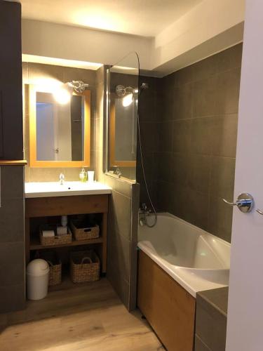 une salle de bain avec une baignoire, un lavabo et un miroir dans l'établissement Oursblanc834, à Huez