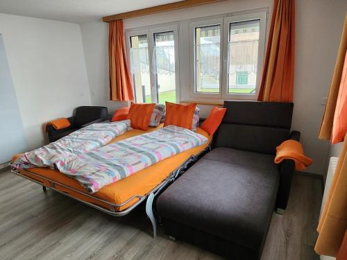 1 cama y 1 sofá en una habitación con ventanas en Steinbock, en Grächen