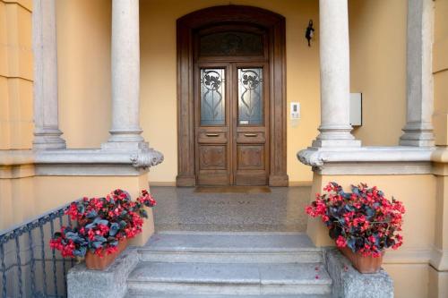 a front door of a house with two potted flowers at Casa Cometa Designer Attic Menaggio in Menaggio