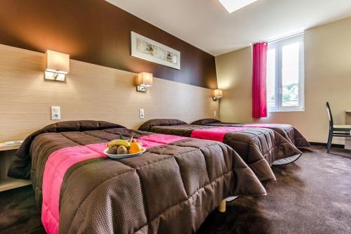 ルルドにあるHôtel Saint Louis de Franceのベッド2台とフルーツのボウルが備わるホテルルームです。
