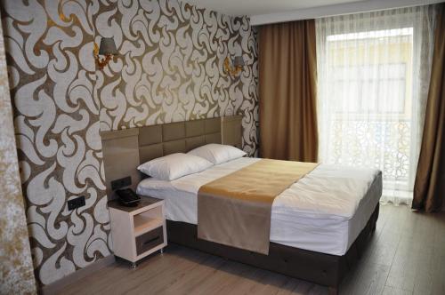 a bedroom with a bed with a patterned wall at Colonia Park Otel in Şebinkarahisar