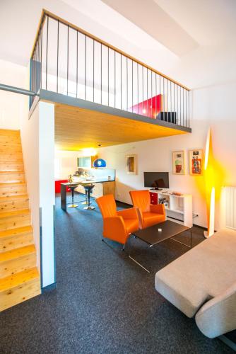 a living room with orange chairs and a staircase at Resort Schloss Auerstedt in Auerstedt