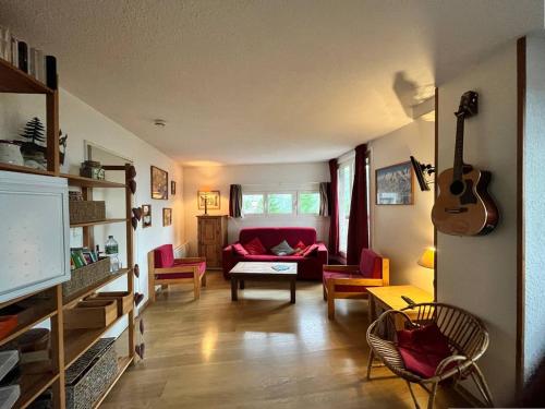 a living room with a red couch and a guitar at Appartement Les Orres, 2 pièces, 8 personnes - FR-1-322-191 in Les Orres