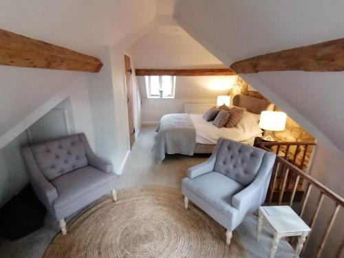a bedroom with a bed and a chair and a table at Merriman Cottage in Chipping Campden