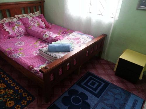 1 dormitorio con cama con sábanas rosas y ventana en Homestay Sri Perhentian Pontian, en Pontian Kecil