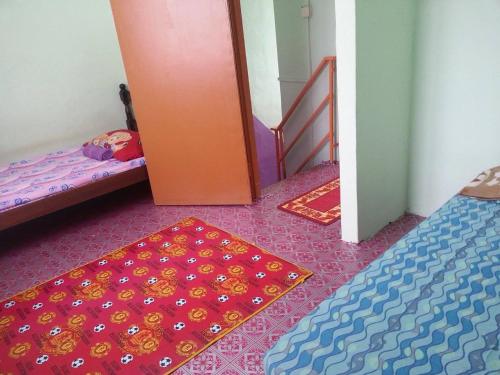 a room with two beds and a door and a rug at Homestay Sri Perhentian Pontian in Pontian Kecil