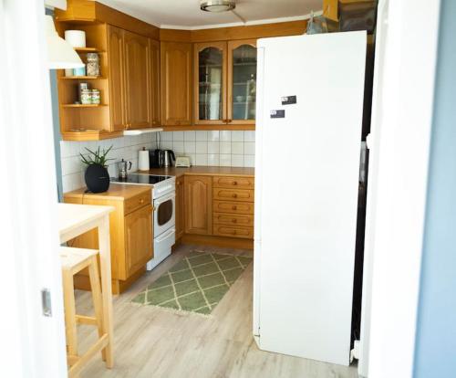 een keuken met houten kasten en een witte koelkast bij 5 minutes to downtown Arendal in Arendal