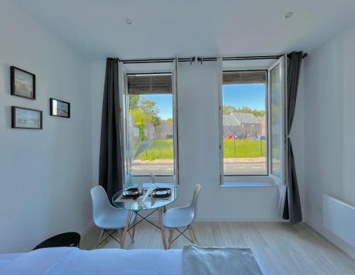 1 dormitorio con mesa, sillas y ventana en Onyx d'Opale, en Calais