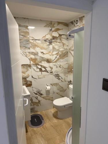 a bathroom with a toilet and a stone wall at Apartman Utrine 1 in Zagreb