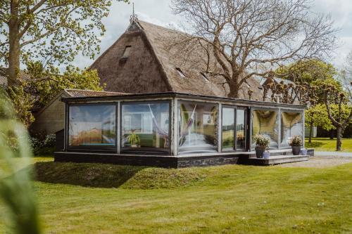 a house with a conservatory in a yard at Tiny Farm House met hot tub. in Menaldum