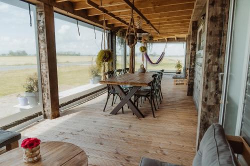 a dining room with a table and chairs and windows at Tiny Farm House met hot tub. in Menaldum