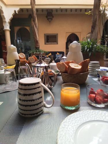 Una mesa con una taza de jugo de naranja y un tazón de pan. en RIAD KERDOUSS, en Marrakech