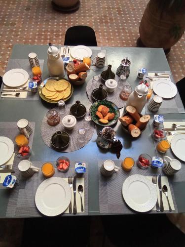 una mesa con platos, utensilios y comida. en RIAD KERDOUSS, en Marrakech