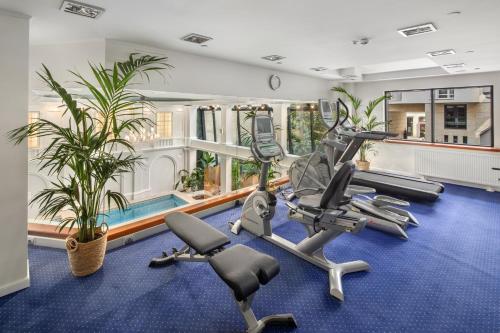 a gym with treadmills and ellipticals in a house at Queen's Court Hotel & Residence in Budapest