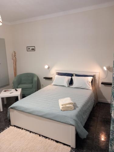 a bedroom with a bed and a green chair at Casa Porta do Sol in Estremoz