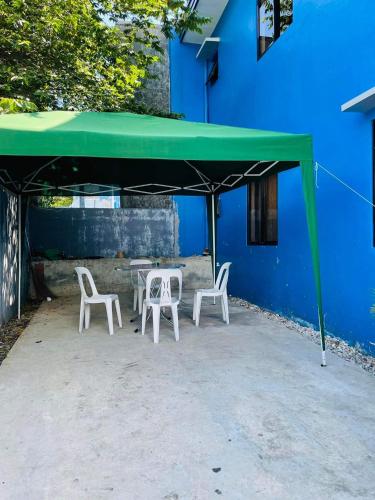 a table and chairs under a green canopy next to a blue building at Marc louie estiaga home for rent in Iloilo City